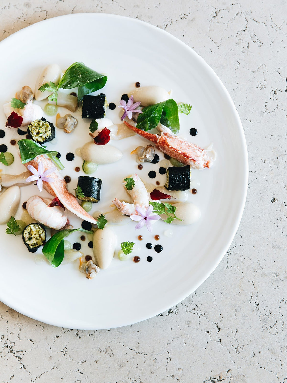 Plat gastronomique délicat avec homard et garnitures colorées sur assiette blanche
