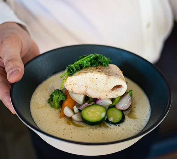 Plat de poisson, sauce légère et mousseuse, légumes d'été croquants, courgettes, radis, carottes, brocolis, surmontés d'un dos de cabillaud